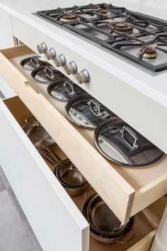 an open drawer in the middle of a kitchen with pots and pans on it