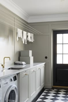 a washer and dryer in a room with a checkered floor, black door and white cabinets