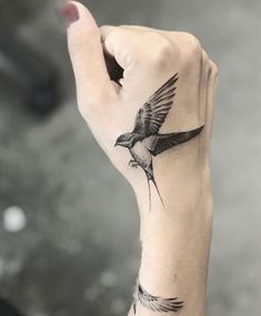 a hand with a bird tattoo on it