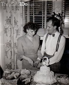 an old black and white photo of two people cutting a cake