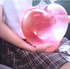 a person holding a pink heart shaped object in their hands