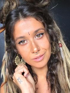 a woman with long hair and piercings on her nose is looking at the camera