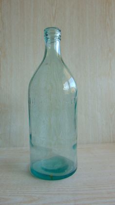 an empty glass bottle sitting on top of a wooden table