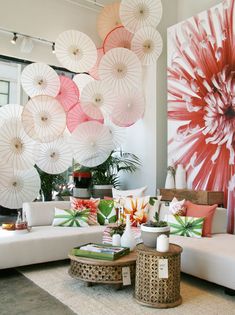 a living room filled with furniture and lots of umbrellas hanging on the wall above it