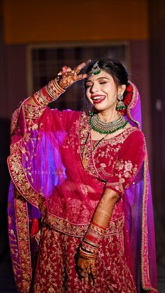 a woman dressed in red and gold poses for the camera with her hands on her head