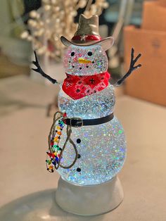 a snowman with a hat and scarf on it's head is sitting on a table