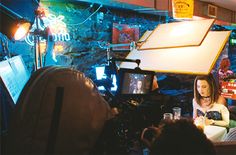 a woman sitting in front of a camera on top of a table next to other people