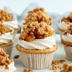 several cupcakes with white frosting and crumbs on top