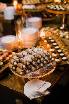 a table topped with lots of desserts next to candles and plates filled with cookies