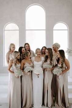 a group of women standing next to each other in front of two large arched windows