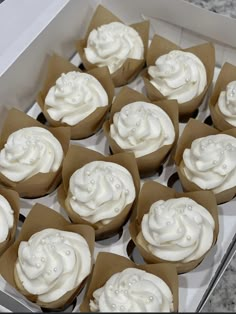 twelve cupcakes with white frosting in a box