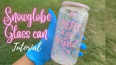 a person wearing blue gloves holding up a pink and white glittered glass bottle with the words snowflake glass can