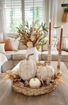 a basket filled with white pumpkins sitting on top of a wooden table next to a couch