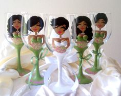 four wine glasses with cartoon characters on them sitting on a white cloth covered tablecloth