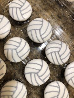 cupcakes with white frosting decorated like volleyball balls on a clear plastic tray