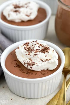 two white bowls filled with chocolate pudding and whipped cream