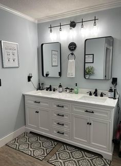 a bathroom with two sinks, mirrors and rugs on the floor in front of it