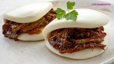 two small sandwiches with meat and sauce on them are sitting on a plate, ready to be eaten