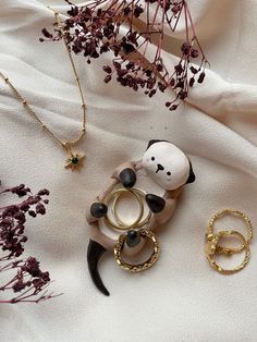 an assortment of jewelry on a white cloth with flowers in the foreground and other items