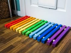 a rainbow colored toy sitting on the floor next to a white door with a window