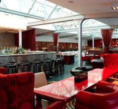 the interior of a restaurant with red chairs