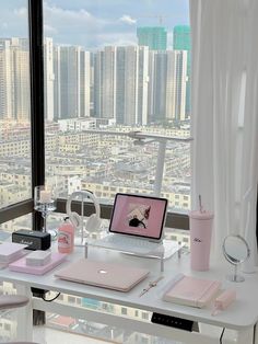 a laptop computer sitting on top of a desk in front of a window overlooking a city