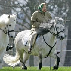 two people riding on the backs of white horses