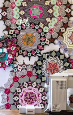 the wall is covered in many colorful pieces of fabric and paper, as well as a sewing machine