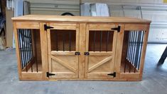 a wooden dog crate with two doors and one door open on the floor in a garage