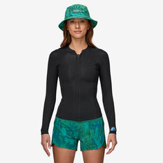 a woman in a wetsuit and hat poses for the camera with her hands on her hips