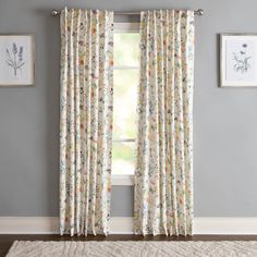 a living room with gray walls and floral curtains on the window sill, along with a rug in front of it