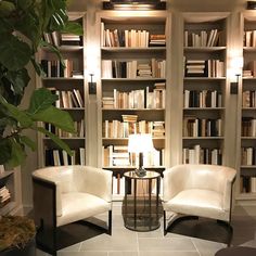 two chairs and a table in front of a bookshelf