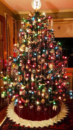 a christmas tree made out of ornaments in a living room with a red rug on the floor