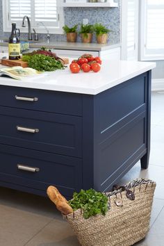 a kitchen island with two baskets on it and vegetables sitting on top of the counter