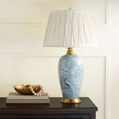 a blue vase sitting on top of a wooden table next to a lamp and book