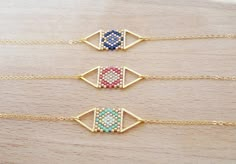 three necklaces with different designs on them sitting on top of a wooden table next to each other