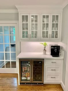 a kitchen with white cabinets and wood flooring next to an open refrigerator freezer