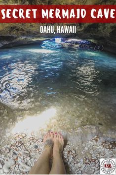 the feet of a person sitting in front of a body of water with rocks and pebbles