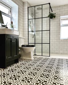 a bathroom with black and white tiles on the floor, shower stall, toilet and sink