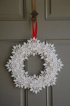 a white snowflake wreath hangs on the front door with a red ribbon around it