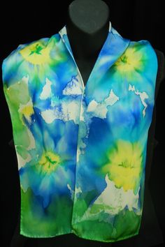 "This is a medium weight silk with a great drape and flow. Silky with an extremely smooth shiny top surface, this is what many people think of when they think \"silk\". This lovely scarf features watercolor flowers in blues and greens with sunny yellow centers.  Approximate Size: 8\" x 54\" (20.3 cm x 137 cm) Each of my scarves, shawls, neckties and other wearables are designed and painted individually, hence no two items are ever the same. Each piece is signed by me. This is wearable art. It is recommended that all hand-dyed/painted silks be washed by hand in cold water. Items without fringe can be washed in the machine. Items with fringe must be washed by hand. Washing instructions included. Please note: Colors you see on your computer screen may vary slightly from the actual colors. Als Hand Painted Blue Silk Scarf For Summer, Hand Painted Green Silk Scarf, Blue Hand Painted Silk Scarf, Silk Scarf Design, Artistic Hand-painted Multicolor Silk Scarf, Elegant Hand-dyed Multicolor Silk Scarf, Hand Painted Silk Scarf, Etsy Bridesmaid Gifts, Hand Painted Silk