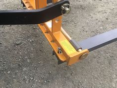 a yellow fork lift sitting on top of a dirt ground next to a metal object