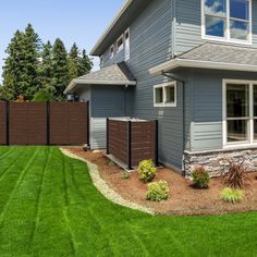 a house that has grass in front of it and a fence around the back yard