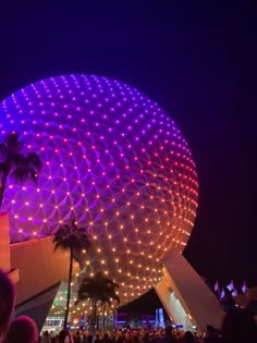 people are standing in front of the spaceship dome at night with bright lights on it