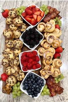 a platter filled with fruit and pastries on top of a wooden cutting board