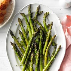 asparagus on a white plate next to croissants