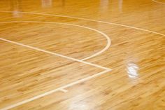 an indoor basketball court with hard wood flooring and white lines on the sidelines