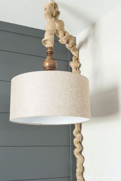 a light fixture hanging from the ceiling in a room with gray walls and wood slats