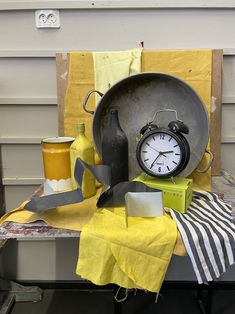 a table topped with a metal pan and clock next to other items on top of it