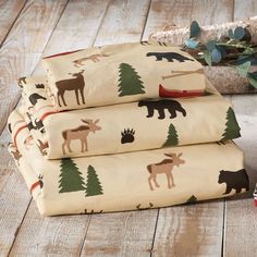 three sheets with moose and bear designs on them sitting on a wooden floor next to a christmas tree